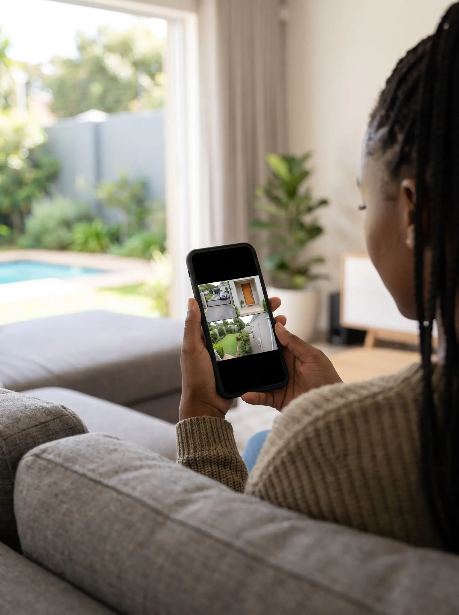 A woman on a couch looking at four camera views of her home on her phone